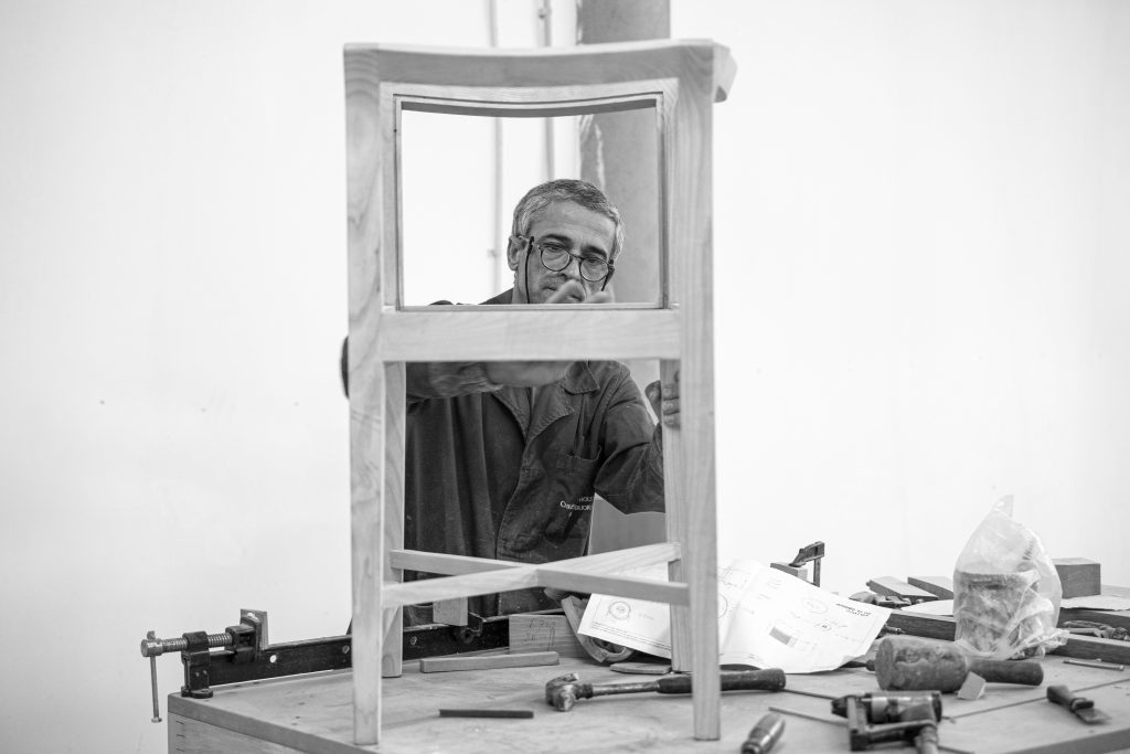 A man is manufacturing a wood piece of furniture